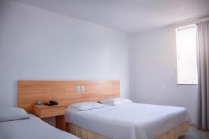 a bedroom with two beds and a window at Pioneiro Hotel in Teixeira de Freitas