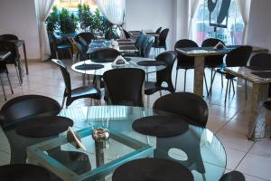 a restaurant with tables and chairs and a glass table at Pioneiro Hotel in Teixeira de Freitas