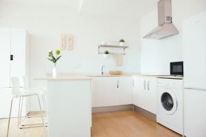 una cucina bianca con lavandino e lavatrice di Estilo nordico Sardinero a Santander