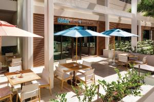 a patio with tables and umbrellas in front of a restaurant at Halepuna Waikiki by Halekulani in Honolulu