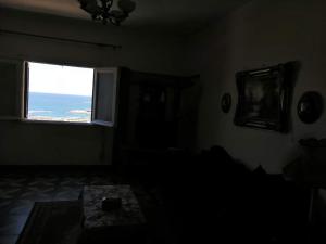 een donkere kamer met een raam en een tafel bij San Stefano apartment on the sea in Alexandrië