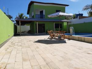 un patio con 2 sillas y una sombrilla junto a una casa en Beach House Maragogi, en Maragogi