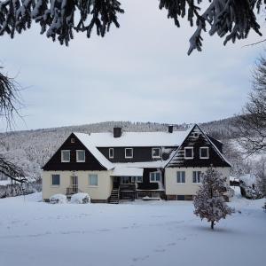 ein großes Haus mit Schnee auf dem Boden in der Unterkunft Ferienwohnung Goldene Höhe in Rechenberg-Bienenmühle