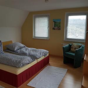 1 dormitorio con 1 cama y 1 silla en Ferienwohnung Goldene Höhe, en Rechenberg-Bienenmühle