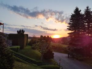 a sunset over a garden with the sun setting at Ferienwohnung Goldene Höhe in Rechenberg-Bienenmühle +6 photos