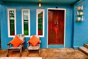 a blue house with two chairs and a red door at Love Bridge House บ้านสะพานรัก in Sangkhla Buri