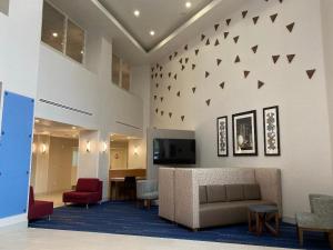 a lobby with a couch and a tv on a wall at Holiday Inn Express & Suites Beaumont - Oak Valley, an IHG Hotel in Beaumont