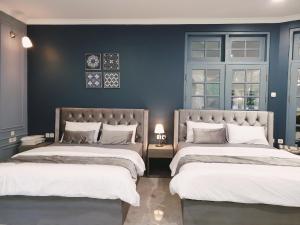 two beds in a bedroom with blue walls at Villa Airis By The Villas 100 in Puncak