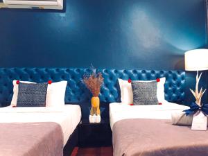two beds in a room with a blue wall at Sabaiday Guesthouse Nimman in Chiang Mai