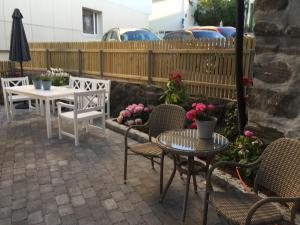 un patio con due tavoli, sedie e fiori di Holsthuset Losji a Grimstad