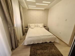 niewielka sypialnia z łóżkiem z białą pościelą i dywanem w obiekcie Adonis Apartment w Nowym Sadzie