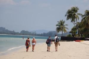
people on a beach with a surfboard at Koh Mook Sivalai Beach Resort in Ko Mook
