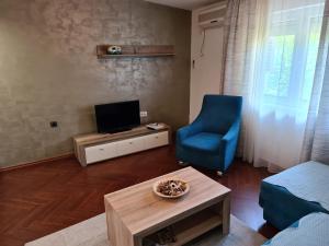 a living room with a blue chair and a television at Apolon in Novi Sad