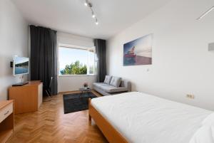a bedroom with a bed and a couch and a window at Beachfront Apartment Karla in Mošćenička Draga