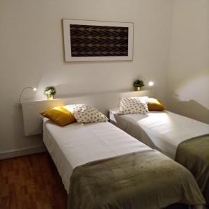 2 camas en una habitación pequeña con una foto en la pared en Tomarhousing - Garden en Tomar