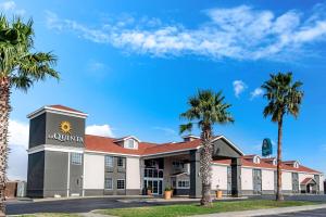 a hotel with palm trees in front of it at La Quinta Inn by Wyndham San Antonio Brooks City Base in San Antonio