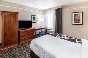 a hotel room with a bed and a desk and a television at La Quinta Inn by Wyndham San Antonio Brooks City Base in San Antonio