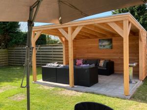eine hölzerne Pergola mit zwei Sofas darunter in der Unterkunft appartement het Stolpje in Julianadorp