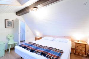 a white bedroom with a bed and a chair at Appartamento MARMOLADA - CANAZEI in Canazei