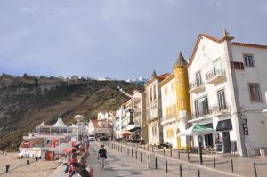 un gruppo di persone che camminano per una strada con edifici di Casa de Zira a Nazaré