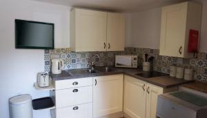 a kitchen with white cabinets and a sink at The Piggery at Moorfield Barns in Praze an Beeble