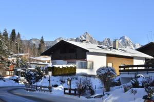 una casa en la nieve con montañas en el fondo en Landhaus Scherl, en Seefeld in Tirol