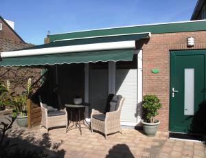 a patio with two chairs and a table and a green door at Duinen Paradijs Zandvoort in Zandvoort