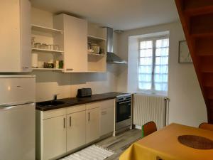 une cuisine avec des placards blancs, une table et une fenêtre dans l'établissement Gite Vénérand, à Acquigny