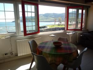 a dining room with a table and chairs and windows at ATICO TORRONTERO in Mundaka