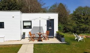 eine Terrasse mit einem Tisch, Stühlen und einem Sonnenschirm in der Unterkunft Hillside Studio in Penzance