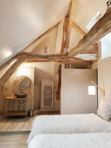 um quarto com uma cama branca e tectos em madeira em Tuilerie de Talouan Maison de maître 4 étoiles écologique et tout confort em Villeneuve-sur-Yonne