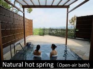 Due donne sono sedute in una piscina di Ryokan with natural hot springs and okonomiyaki Miyajima-an Hiroshima a Miyajima