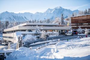 een gebouw in de sneeuw met bergen op de achtergrond bij Edelweiss Stenna Cavorgia in Flims