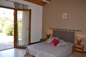 a bedroom with a bed with a pink pillow on it at Village de gîtes Les Olivettes in Saint-Dézéry +40 photos