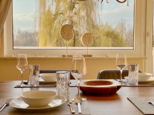 een houten tafel met glazen, kommen en borden erop bij Ferien-Apartment Eisvogel im Naturschutzgebiet mit Privatstrand in Friedrichshafen