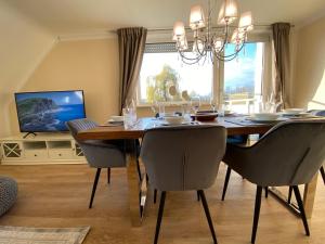 a dining room with a table and chairs and a television at Ferien-Apartment Eisvogel im Naturschutzgebiet mit Privatstrand in Friedrichshafen
