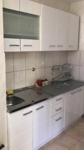 uma cozinha com armários brancos e um lavatório em Private Apartman em Berane