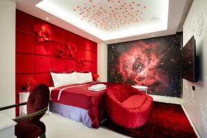 1 dormitorio con 1 cama roja y 2 sillas en AURORA MOTEL en Taichung