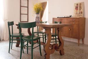una mesa de madera con 4 sillas verdes y un tocador en Ritornello B&B, en Poviglio