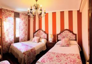 ラグアルディアにあるLa Casa de Begoñaのオレンジと白のストライプを用いた客室内のベッド2台