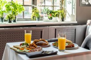 une table avec deux assiettes de nourriture et deux verres de jus d'orange dans l'établissement Kravt Sadovaya Hotel, à Saint-Pétersbourg