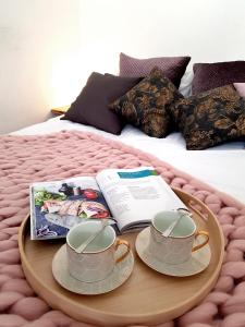 una bandeja con dos tazas y un libro en una cama en Apartament Peowiaków Kings Deluxe, en Lublin