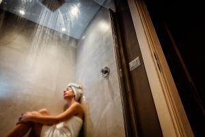 a woman sitting in a shower with a towel on her head at B&B Palazzo Cerami in Catania