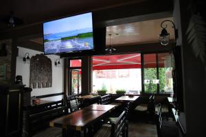 a restaurant with tables and a flat screen tv on the wall at Pension Kokett in Cîmpulung