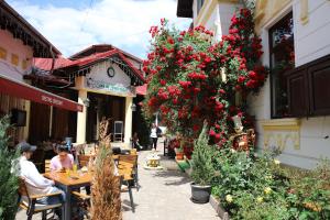 a street with flowers and people sitting at tables at Pension Kokett in Cîmpulung