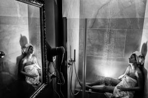 a woman sitting in a shower in a mirror at B&B Palazzo Cerami in Catania