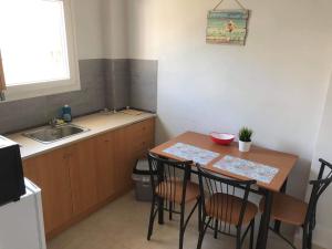 a kitchen with a table and chairs and a sink at Samakovlis Apartments in Néa Michanióna