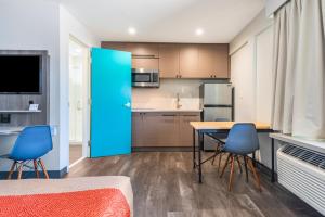 Una cocina con una mesa y dos sillas azules. en Solo Motel Broadway, en Los Ángeles