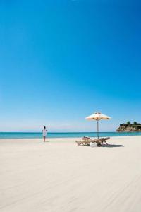 uma pessoa de pé numa praia com um guarda-sol em Star Beach Resort em Makrýgialos