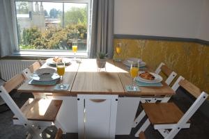 a wooden table with glasses of orange juice and food on it at Maytree 2 Bed Apartment - STAYSEEKERS in Salisbury